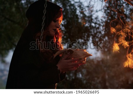 Woman disguised as a witch holding a skull in her hands