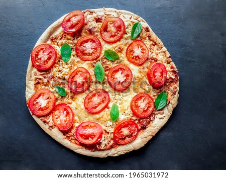 closed up on pizza with tomato, basil, chicken and large cheese on black background and with space for text
