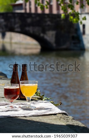 Tasting of Belgian beer on open cafe or bistro terrace with view on medieval houses and canals in Bruges, Belgium in sunny day