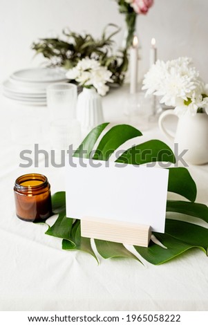 Mock up label the blank menu frame in bar restaurant, Stand for booklets with white paper, wooden tent card on monstera leaf on restaurant table