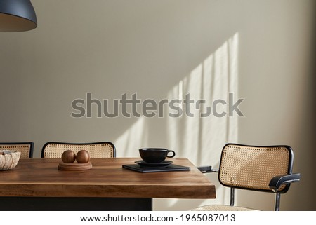 Minimalist concept of dining room interior with wooden family table, design chairs, cup of coffee, tableware, beige wall and personal accessories. Copy space. template.