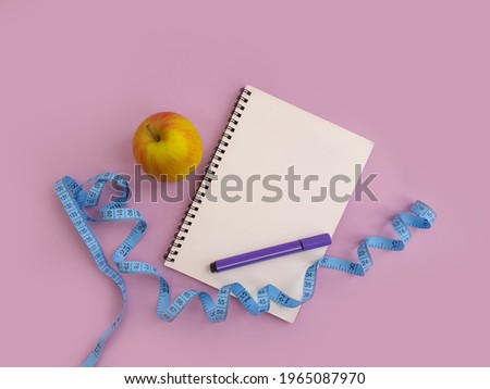notebook, measuring tape, apple on a colored background