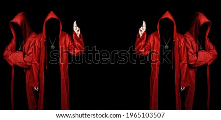 People dressed in a red robes looking like a cult members on a dark background. Pointing up with fingers. Ghostly figure. Sectarian. Copy space.  Royalty-Free Stock Photo #1965103507