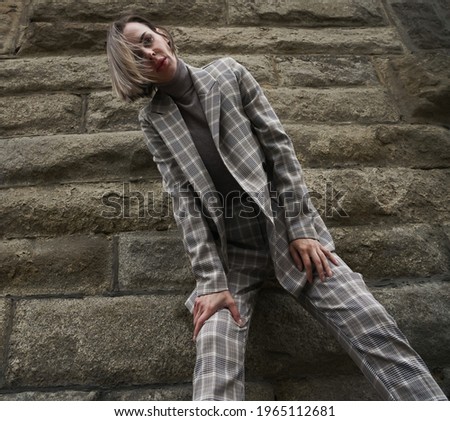 stylish Business woman standing on stoned wall background.  businesswoman with blonde hair wearing suit in a cage. 