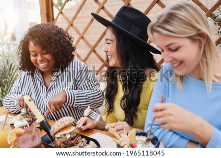 Young multiracial friends having breakfast outdoors in restaurant - Focus on asian girl face