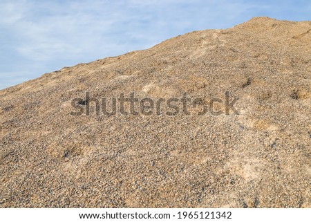 Mountain of sandy gravel mixture on the background of the sky.
