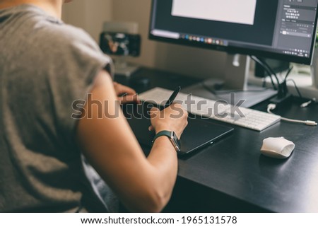 Woman designer, retoucher, photographer or artist drawing something on graphic tablet at the home office Royalty-Free Stock Photo #1965131578