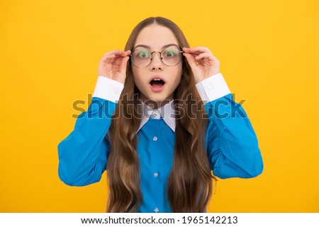 Shocked school aged girl child in spectacles with amazed look yellow background, amazement.