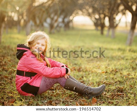 happy girl on grass in autumn garden