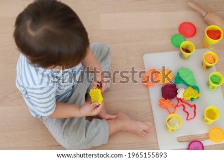 Top view of baby boy playing with clay dough focus on hand. Happy child learn molding development. Kid education Montessori concept.