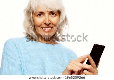 grandmother is talking to her grandchildren by phone, smiling and greeting them.