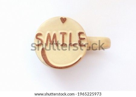 A smile on the bottom of the mug. The mug is upside down on a white background. The concept of good morning, good mood.