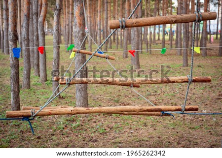 A ladder made of ropes and sticks in the forest in the trees.