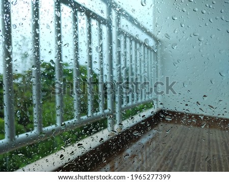 Terrace on a rainy day There were water droplets on the glass, and there was a green view of the trees in the background.