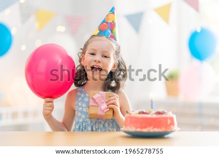 The kid is blowing out the candles on the cake. Child is celebrating birthday.