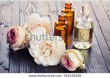 Essential aroma oil with roses on wooden background. Selective focus.