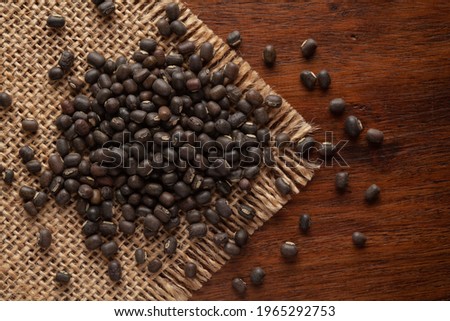 Macro Close-up of Organic Black Gram (Vigna mungo) or Whole Black Urad Daal on Jute mat and wooden top.