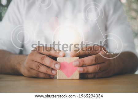 Man hand holding light bulb with pink heart and empty diagram. Love concept