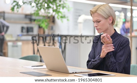 Stressed Woman Working on Laptop having Wrist Pain in Office 