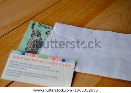 The US federal stimulus check showing the statue of liberty with envelop next to social security card on table. People with SSN can receive the Covid 19 pandemic payment. Relief Program concept. 