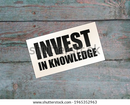 Invest in Knowledge words on card on wooden table. Business education concept.