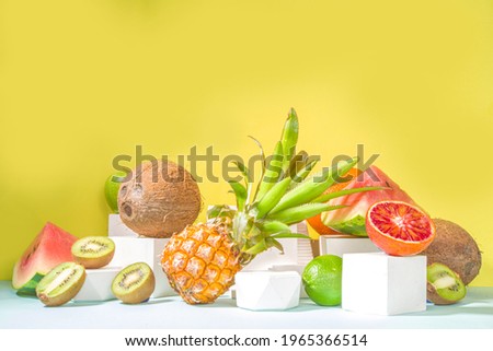 Summer composition, Various tropical fruits, on modern bright yellow background with podiums, copy space. Holiday and vacation, healthy food concept copy space