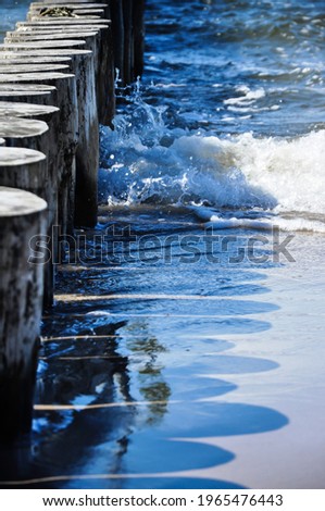 
View of the Baltic Sea with light surf. In the foreground a row of breakwaters