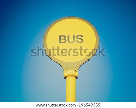 Vintage retro looking Yellow bus stop sign over blue sky background