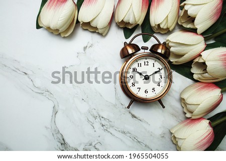 Vintage alarm clock and tulip flower bouquet on marble background