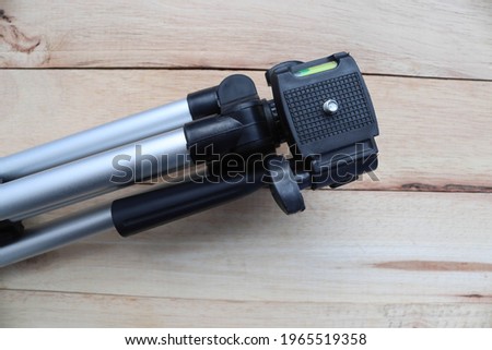 Head of mini camera tripod isolated of wooden background closeup.