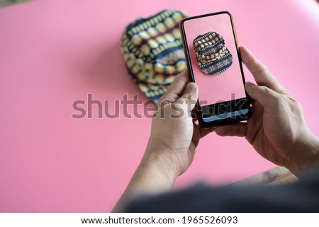 Men take photos of hats with their mobile phones or digital cameras on smartphones to post for sale online on the Internet.