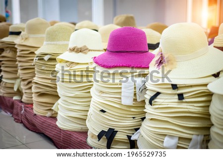 Many summer ladies straw hats pile in a row for sale at the market. Handcrafted women  pink straw hats on shopping mall. Colorful woman fasion style design for retro clothing Royalty-Free Stock Photo #1965529735