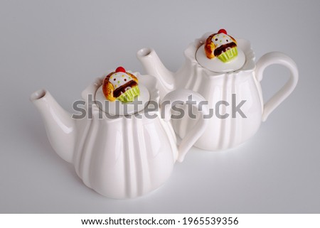 Two white teapots for tea. Dishes for tea drinking. Cupcake on a lid Muffin