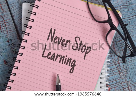 Never Stop Learning wording with spectacles and pen over a wooden background with vintage effect. Motivational and inspirational concept. Selective focus image.