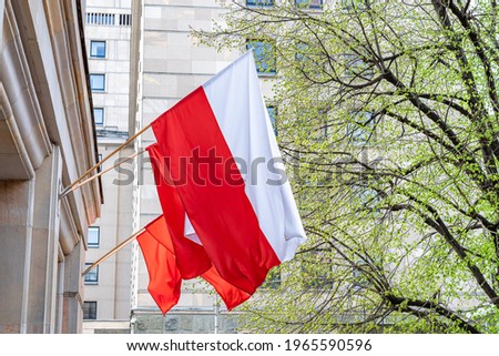 Flag of Poland on facade of a building waving in the wind on sunny day. Celebrating Polish National Flag Day Royalty-Free Stock Photo #1965590596