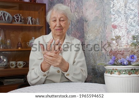 Elderly woman applying moisturizing lotion cream on hand palm, easing aches. Senior old lady experiencing severe arthritis rheumatics pains, massaging, warming up arm.