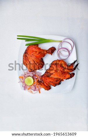  Tandoori chicken Indian style chicken curry pot-roasted leg on white triangle dish over white background with spicy and lemon, onion, carrot and Red Color . and Delicious Tandoori chicken leg pies