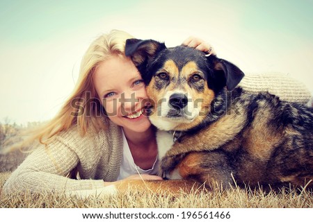 a happy young woman and her German Shepherd dog are laying on the grass outside hugging. Vintage style color. Royalty-Free Stock Photo #196561466