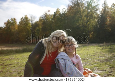 Grandma and granddaughter at a pumpkin patch enjoying the fall activity. Theme of multi-generational family activities.