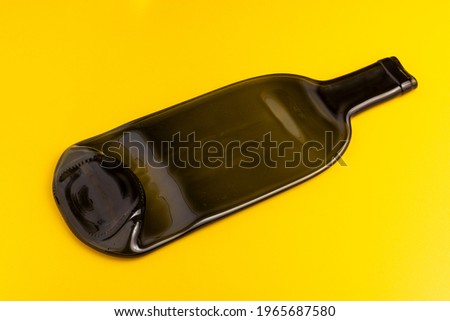 Flattened wine bottle serving plate. Recycled wine bottle plate on yellow background.