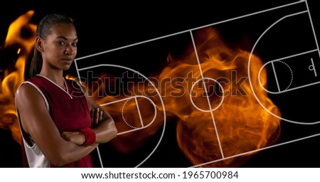 Composition of female basketball player over basketball court and flames. sport and competition concept digitally generated image.