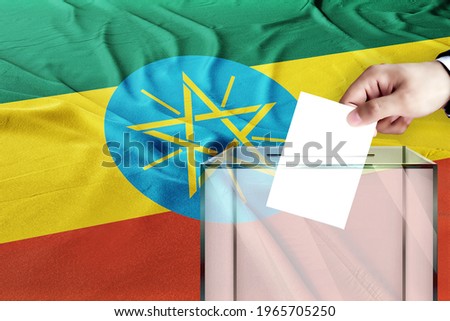 ethiopia flag, ethiopia  the symbol of elections Male hand puts down a white sheet of paper with a mark as a symbol of a ballot paper against the background
