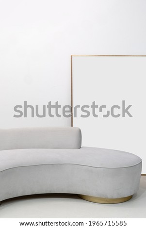 Vertical shot of grey velvet sofa and mockup painting against clear copy space wall on background. Concept of minimalist living room interior in contemporary apartment