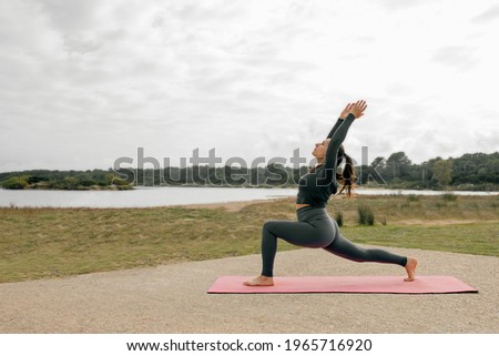 Woman in nature practicing yoga, doing Virabhadrasana A posture