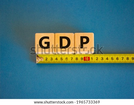 GDP, gross domestic product symbol. The word GDP, gross domestic product on cubes arranged behind the ruler on beautiful blue background. Copy space. Business and GDP rate concept.