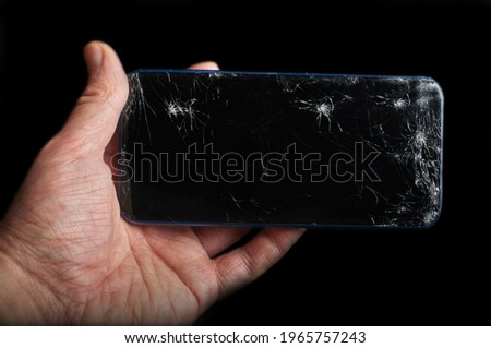 smartphone with a broken display in hand on a black background