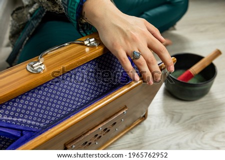 Close-up of hand playing a shruti, a musical instrument of Indian origin. Indian harmonium. Woman performing kirtan, chanting mantras. Royalty-Free Stock Photo #1965762952