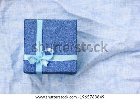 A small gift in a blue box is placed on the home tablecloth. An unexpected surprise.