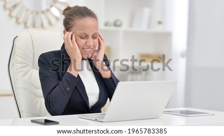 Stressed African Businesswoman with Laptop having Headache in Office 