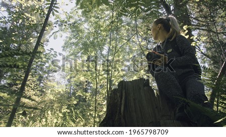 Traveler photographing scenic view in forest. One caucasian woman shooting nice magic look. Girl take photo video on dslr mirrorless camera. Professional photographer travel with backpack. Outdoor.